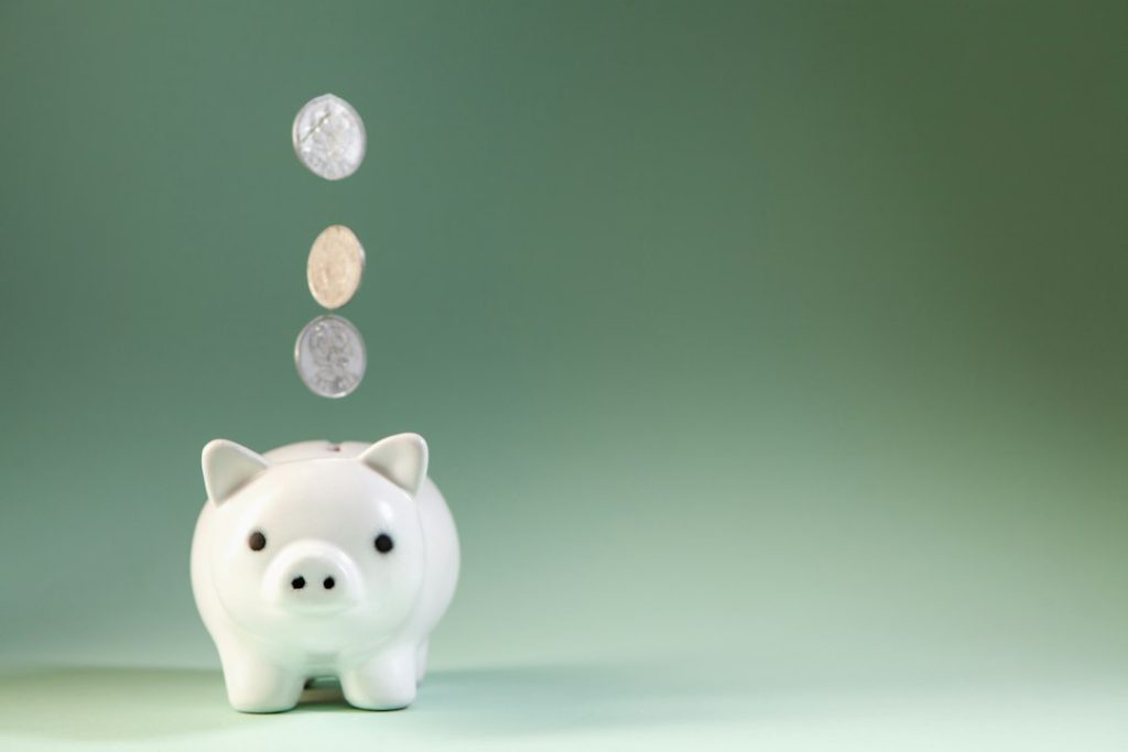 Monedas cayendo en una alcancía, negocios que puedes empezar con 10 dólares