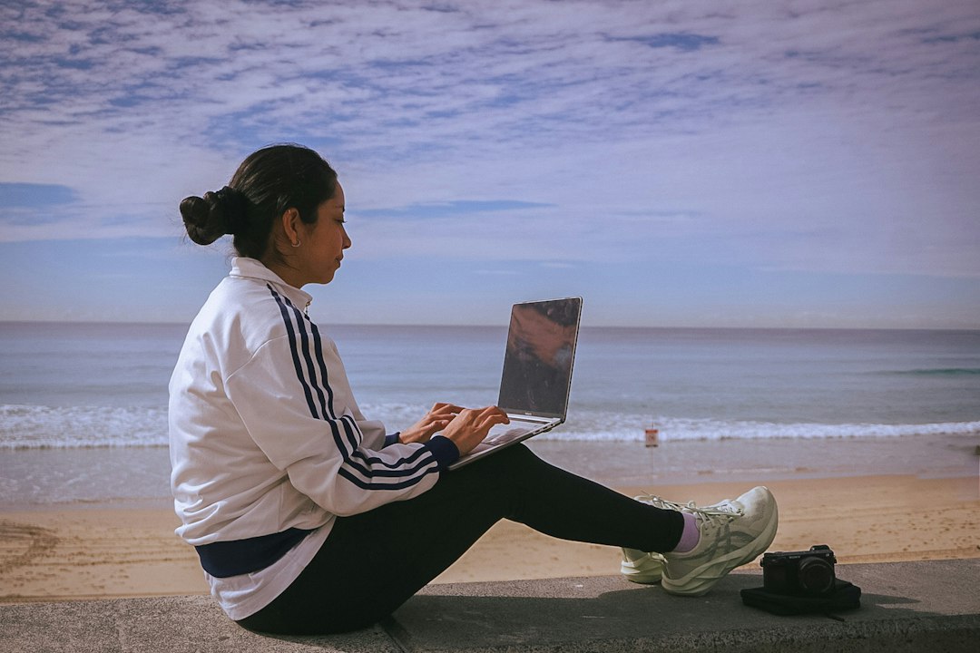 Nómada digital trabajando con su portátil junto a la playa