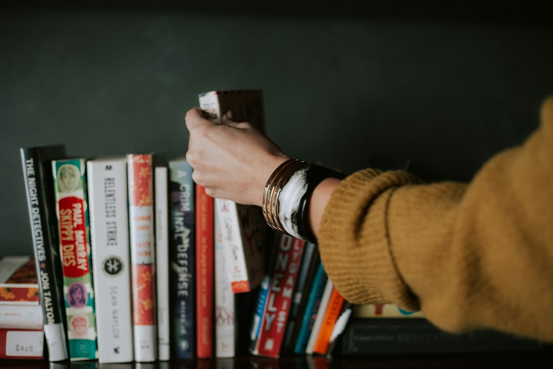 Persona eligiendo un libro de la estantería para invertir en sí misma, consejo de Warren Buffett