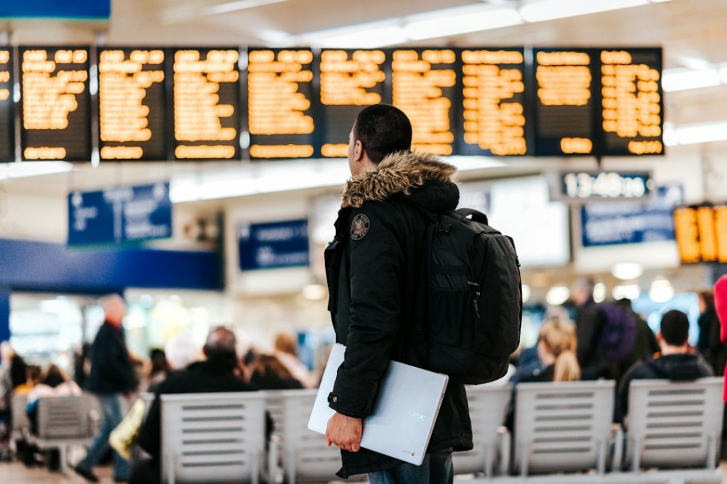 Viajero mirando el panel de vuelos en un aeropuerto, becas para chilenos para estudiar en el extranjero